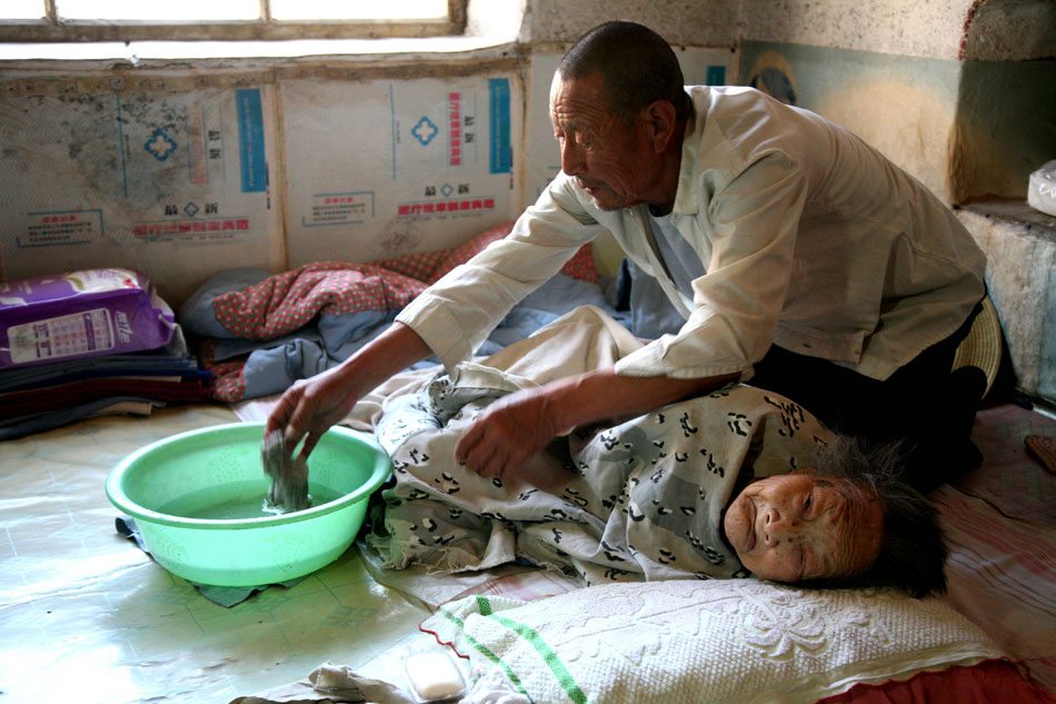 Wang cleans his mother's body on May 29, 2013. (Xinhua/Ren Lihua)