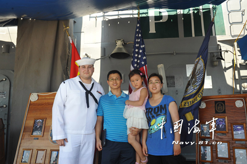 A local family takes a group photo on June 1 with a U.S. sailor while visiting the guided-missile cruiser Shiloh of the U.S. Navy, which is paying a port call to Zhanjiang city of south China's Guangdong Province. (chinamil.com.cn/Tang Zhuoxiong)