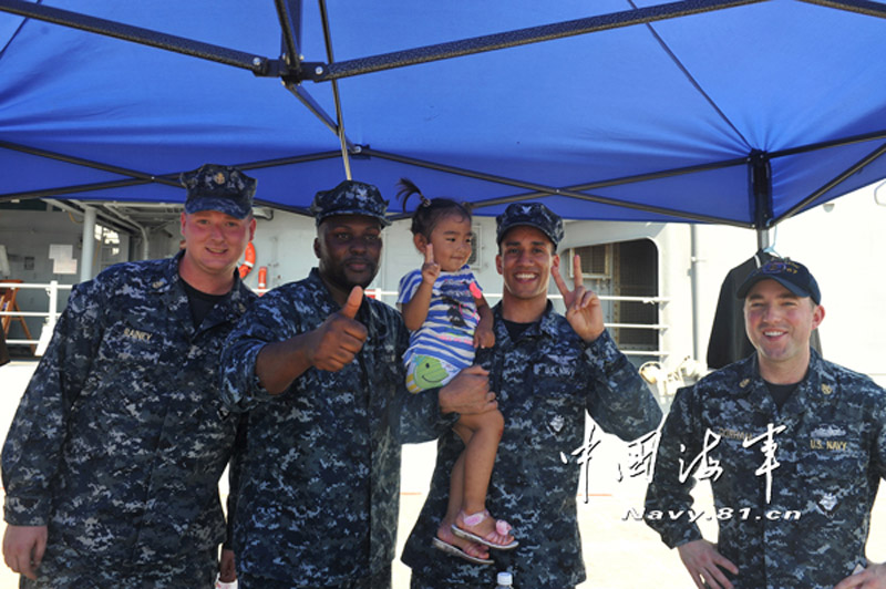 Four U.S. sailors take a group photo with a Chinese little girl on the guided-missile cruiser Shiloh, June 1, 2013. (Photo by Tang Zhuoxiong and Gao Yi)