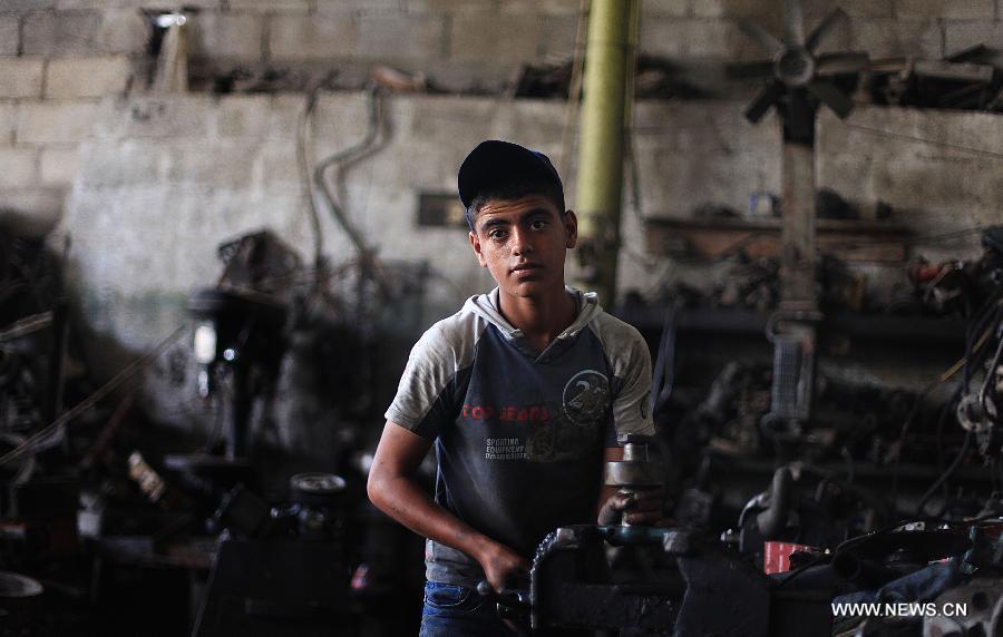 A Palestinian boy works at a garage for repairing cars in Gaza city on June 4, 2013. Many boys left school to work in many different jobs to support their families. Child labor is widespread in the Gaza Strip because of the high rates of poverty. (Xinhua/Yasser Qudih) 