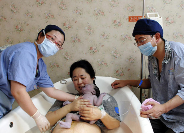 Mother Lu (C) holds her new baby boy, who was born in water, at Shanghai Changning Maternity & Infant Health Hospital, on June 3, 2013. 