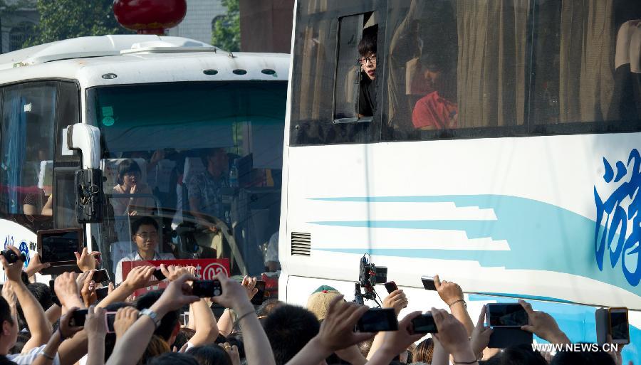 Coaches full of students leave the school, slowly moving in the crowd on Jun. 5, 2013. On this day, over 11,000 students from Maotanchang High School and Jin’an High School in Maotan town, Liu’an, Anhui province left for the university entrance exam places in Liu’an.(Photo/Xinhua)