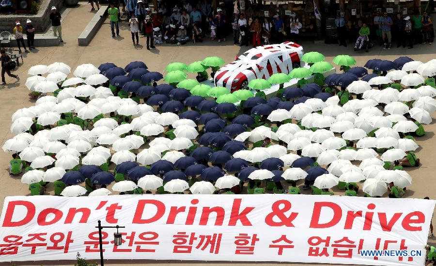 People holding umbrellas take part in a flash mob against drunk driving at Namsan Hanok Village in Seoul, South Korea, June 5, 2013. (Xinhua/Park Jin-hee)