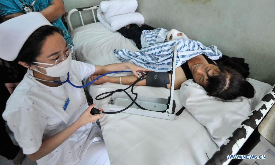 A nurse checks the blood pressure of a woman injured in a fire accident in hospital in Changchun, capital of northeast China's Jilin Province, June 5, 2013. A fire broke out at a poultry processing workshop owned by the Jilin Baoyuanfeng Poultry Company in Mishazi Township in the city of Dehui on early Monday morning. The fire killed 120 people and injured 77 others. (Xinhua/Wang Haofei) 