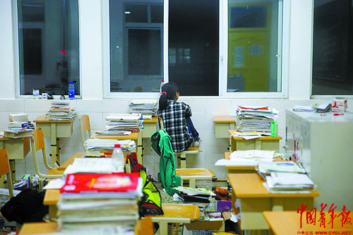 A student in grade 12 sits at the window after self-study at night in the classroom on weekend in Baoxing High School. (Photo/ China Youth News)