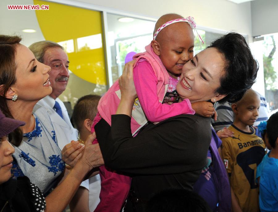 Peng Liyuan (1st R), wife of Chinese President Xi Jinping, accompanied by Mexico's first lady Angelica Rivera, hugs a child patient during her visit to Federico Gomez Children's Hospital, in Mexico City, Mexico, June 4, 2013. (Xinhua/Rao Aimin) 