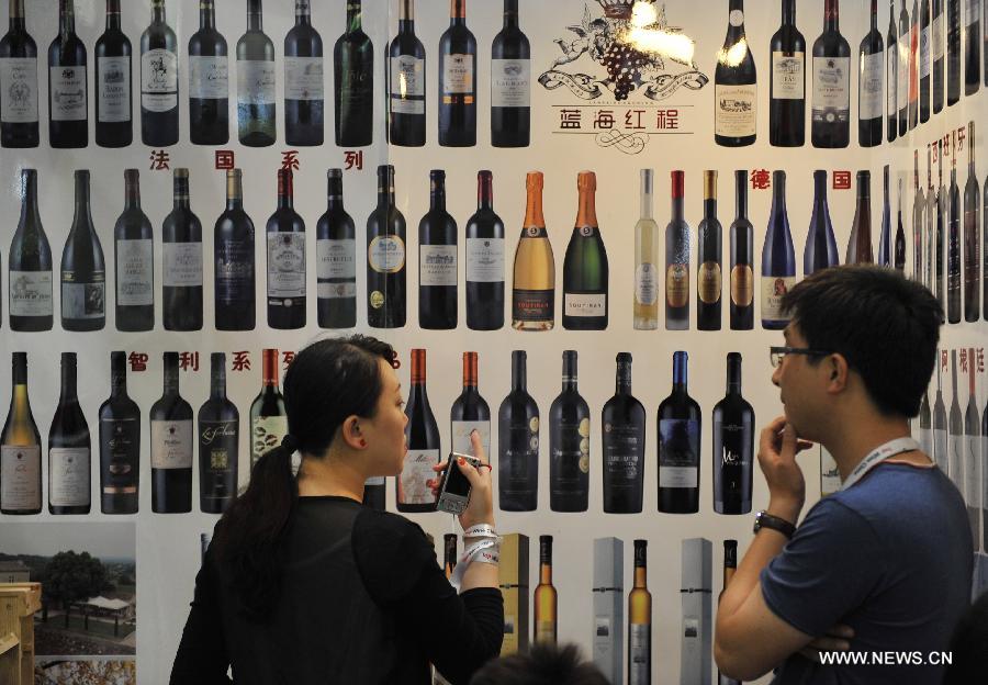 An exhibitor (L) introduces wine to a visitor at the Top Wine China 2013 Expo in Beijing, capital of China, June 5, 2013. The 3-day expo kicked off on June 4, with over 5,000 wine brands from home and abroad participated. (Xinhua/Lu Peng) 