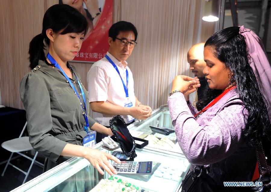 A buyer from Maldives chooses South Korean Jewelry at the first China-South Asia Expo in Kunming, capital of southwest China's Yunnan Province, June 6, 2013. The five-day China-South Asia Expo opened here on Thursday, attracting over 1,400 exhibitors from Asian countries and regions. (Xinhua/Chen Haining)
