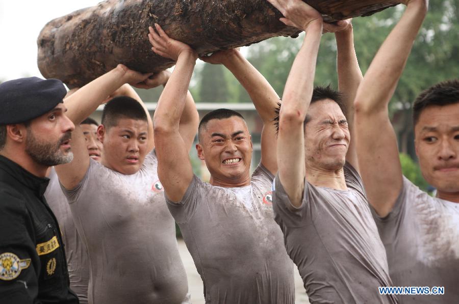 Trainees carry a log during a VIP security training course at the Genghis Security Academy in Beijing, capital of China, June 6, 2013. Some 70 trainees, including six females and three foreigners, will receive intensified training at the bodyguard camp for over 20 hours per day in a week. One third of them will be eliminated. (Xinhua/Liu Changlong)