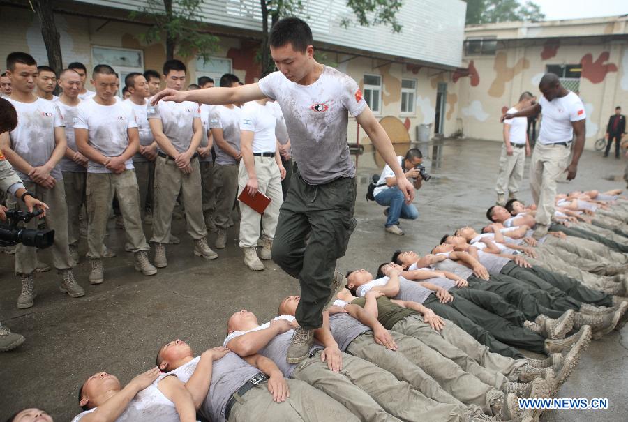Trainees trample on fellow trainees during a VIP security training course at the Genghis Security Academy in Beijing, capital of China, June 6, 2013. Some 70 trainees, including six females and three foreigners, will receive intensified training at the bodyguard camp for over 20 hours per day in a week. One third of them will be eliminated. (Xinhua/Liu Changlong)
