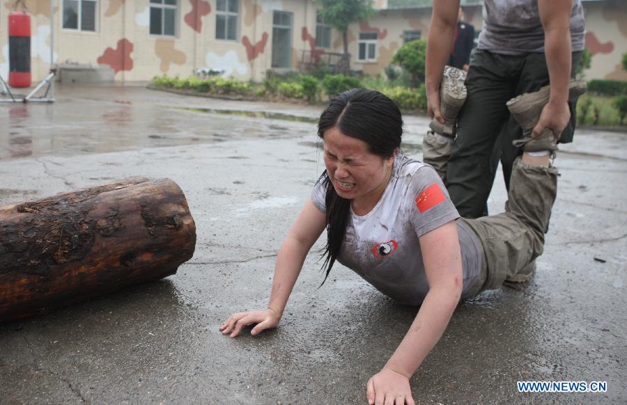 A female trainee reacts during a VIP security training course at the Genghis Security Academy in Beijing, capital of China, June 6, 2013. Some 70 trainees, including six females and three foreigners, will receive intensified training at the bodyguard camp for over 20 hours per day in a week. One third of them will be eliminated. (Xinhua/Liu Changlong)