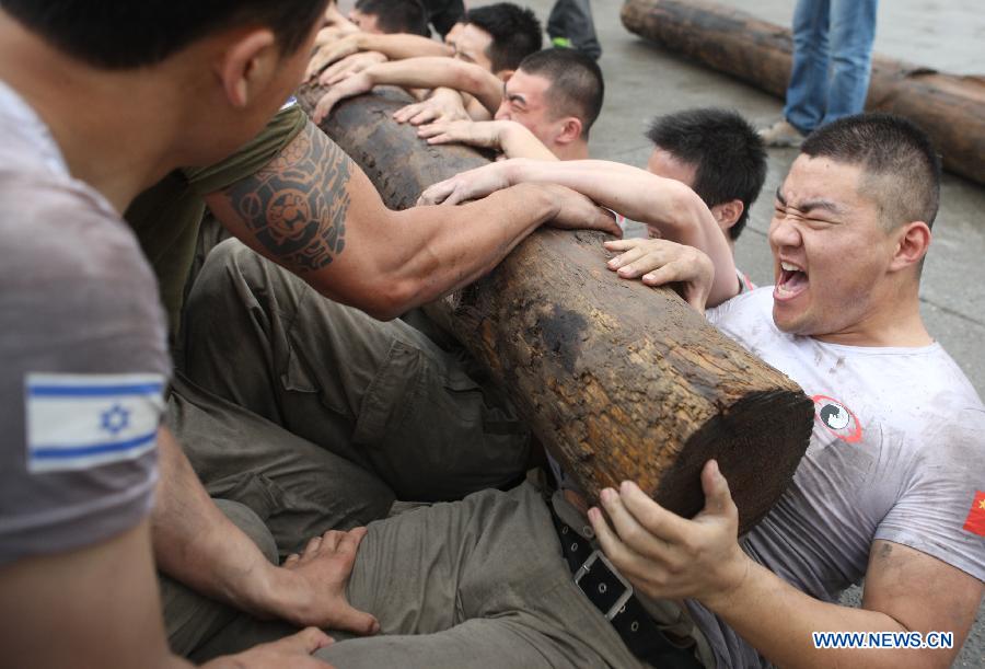 Trainees lift a log during a VIP security training course at the Genghis Security Academy in Beijing, capital of China, June 6, 2013. Some 70 trainees, including six females and three foreigners, will receive intensified training at the bodyguard camp for over 20 hours per day in a week. One third of them will be eliminated. (Xinhua/Liu Changlong)