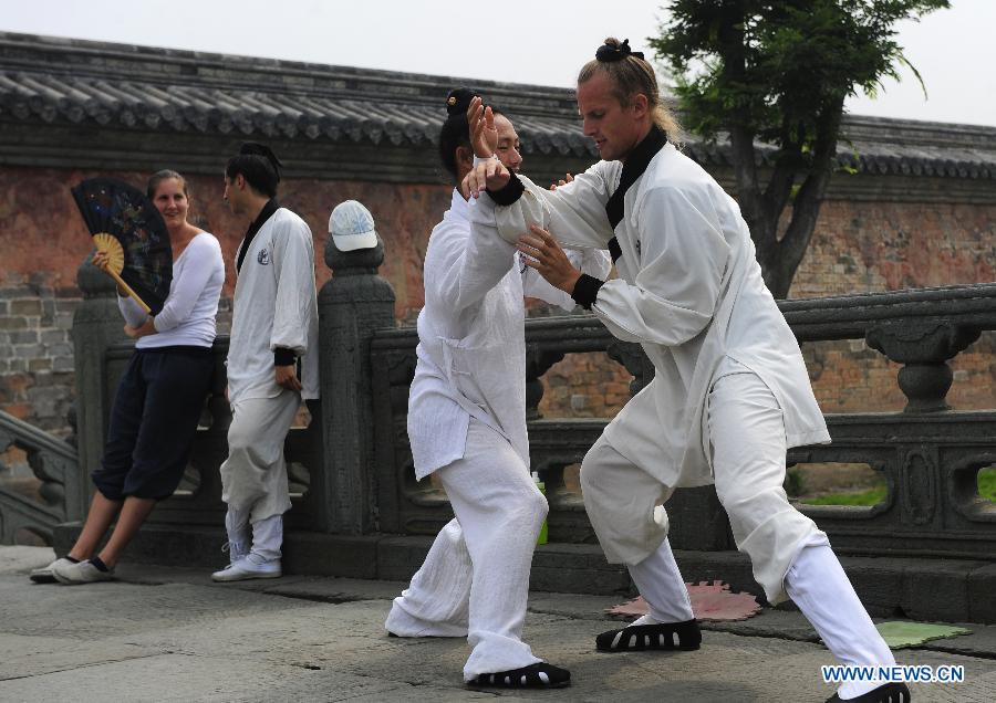 A foreign learner practises Chinese martial arts movements with his master at the Yuxu Palace on Wudang Mountain, known as a traditional center for the teaching and practice of martial arts, in central China's Hubei Province, June 5, 2013. (Xinhua/Hao Tongqian) 