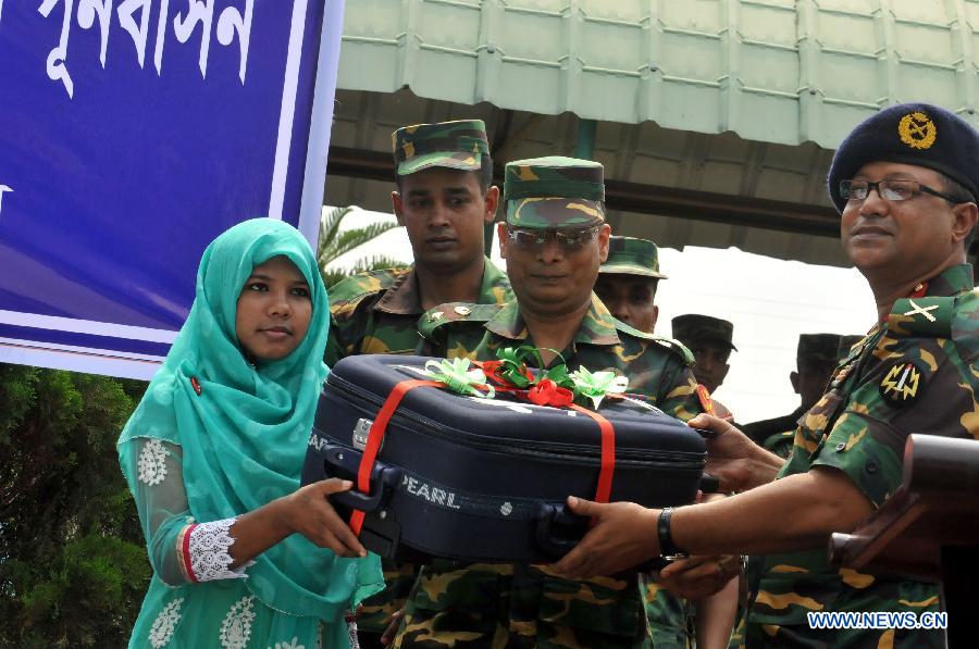 Reshma (L), a young female garment worker, receives a gift in Savar on the outskirts of Dhaka, Bangladesh, June 6, 2013. Miraculous Bangladeshi building collapse survivor Reshma will join Starwood Hotels and Resorts Worldwide, one of the top global hotel chains, as an ambassador, officials said Thursday. Eight-storey building Rana Plaza collapsed in Savar on the outskirts of the capital Dhaka on April 24, leaving at least 1,127 people dead. (Xinhua/Shariful Islam)