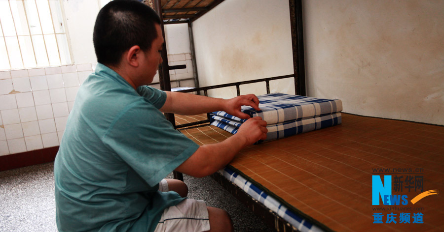 Wang makes his bed in Chongqing rehab center. (Photo/Xinhua)