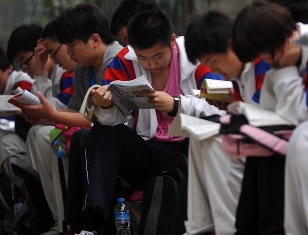 Students study while waiting outside a test site in Beijing, June 7, 2013. [Photo/Xinhua]