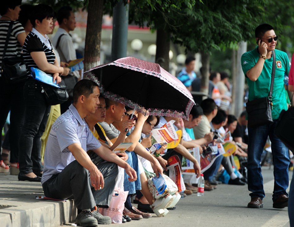 Parents wait outside an examination site in Lanzhou, Gansu Province, on June 7. Some 9.12 million applicants are expected to sit this year's college entrance exam, down from 9.15 million in 2012, a spokeswoman for the Ministry of Education (MOE) said on Wednesday. [Photo/Xinhua] 