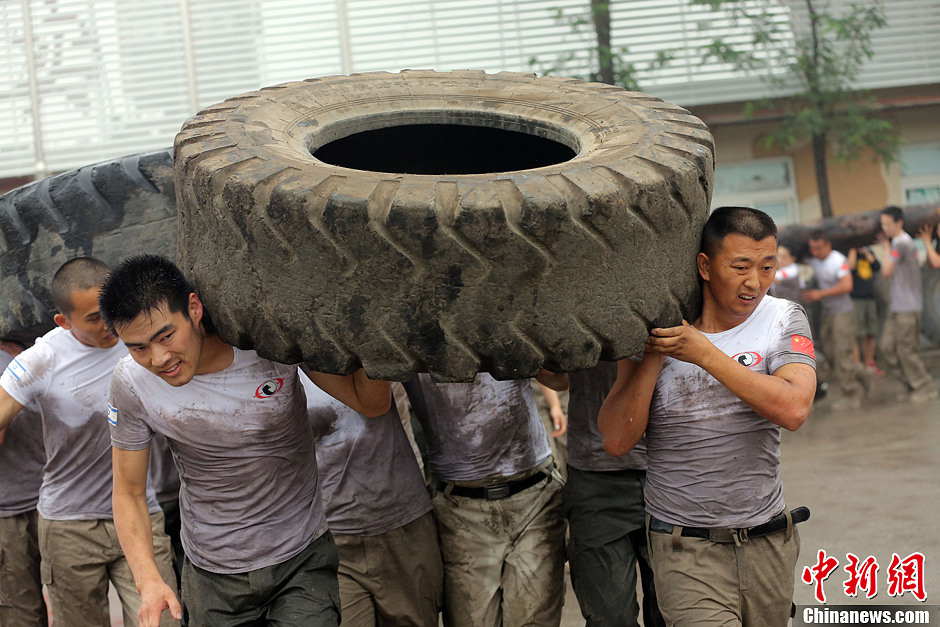 Trainees lift a tire during a VIP security training course at the Genghis Security Academy in Beijing, capital of China, June 6, 2013. More than 70 trainees, including six women and three foreigners will receive high-intensity training for VIP security at a bodyguard camp in Beijing. They will train over 20 hours per day for one week. One third of them will be eliminated. (Photo/ Chinanews.com)