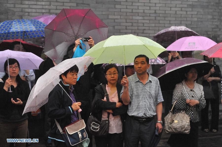 Parents wait in rain while their children are taking the national college entrance exam in Beijing, capital of China, June 7, 2013. Some 9.12 million applicants are expected to sit this year's college entrance exam. (Xinhua/Chen Yehua)