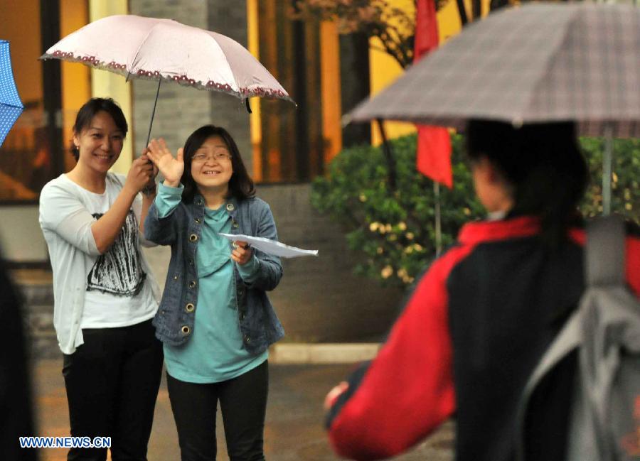 A teacher waves to her student taking the national college entrance exam in Beijing, capital of China, June 7, 2013. Some 9.12 million applicants are expected to sit this year's college entrance exam. (Xinhua/Li Wen)
