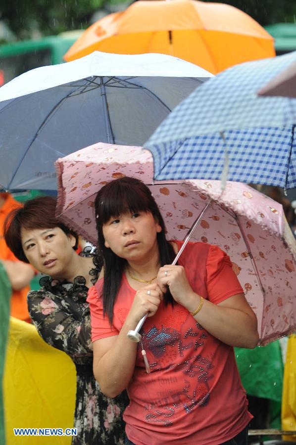Mothers wait in rain for their kids taking the national college entrance exam in Hangzhou, capital of east China's Zhejiang Province, June 7, 2013. Some 9.12 million applicants are expected to sit this year's college entrance exam. (Xinhua/Ju Huanzong)