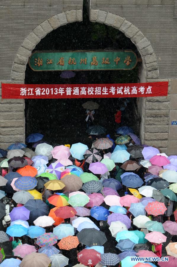 Parents holding umbrellas wait in rain as their children taking the national college entrance exam at the Hangzhou High School in Hangzhou, capital of east China's Zhejiang Province, June 7, 2013. Some 9.12 million applicants are expected to sit this year's college entrance exam on June 7 and 8. (Xinhua/Ju Huanzong)