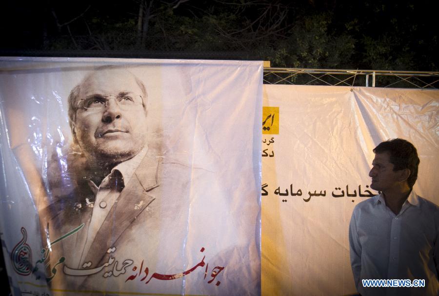 A man stands beside a poster of Tehran Mayor and presidential candidate Mohammad-Baqer Qalibaf during a campaign rally in Shahr-e Rey, south of Tehran, Iran, on June 7, 2013. Iran's 11th presidential election is scheduled for June 14. (Xinhua/Ahmad Halabisaz) 