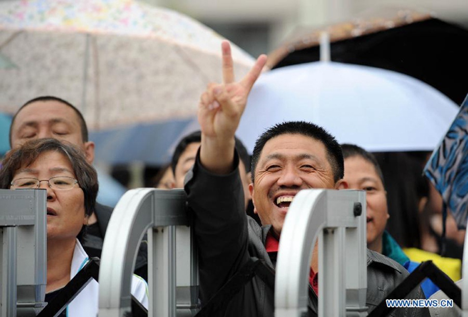 A man flashes a victory sign to his kid taking the national college entrance exam in Heihe, northeast China's Heilongjiang Province, June 7, 2013. Some 9.12 million applicants are expected to sit this year's college entrance exam. 