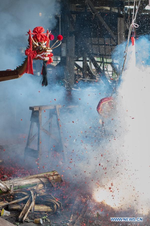 Firecrackers are burnt during a launching ceremony for new dragon boat at the Chenhanhui Shipyard at Shangjiao village in Guangzhou, capital of South China's Guangdong province, June 6, 2013. Chenhanhui Shipyard has been busy making new dragon boats and renovating old ones for the upcoming Dragon Boat Festival that falls on June 12 this year. People in many parts of China have the tradition to hold dragon boat races during the festival.(Photo/Xinhua) 