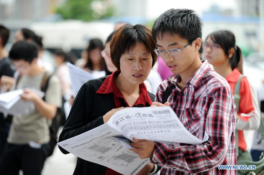 A mother and her son check job information at a job fair in Hangzhou, capital of east China's Zhejiang Province, June 8, 2013. The job fair offered over 25,000 job posts to college graduates. (Xinhua/Ju Huanzong)