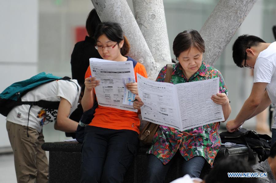 A mother (2nd R) and her daughter check job information at a job fair in Hangzhou, capital of east China's Zhejiang Province, June 8, 2013. The job fair offered over 25,000 job posts to college graduates. (Xinhua/Ju Huanzong)