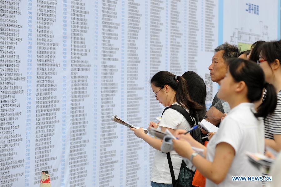 Students and parents check job information at a job fair in Hangzhou, capital of east China's Zhejiang Province, June 8, 2013. The job fair offered over 25,000 job posts to college graduates. (Xinhua/Ju Huanzong)
