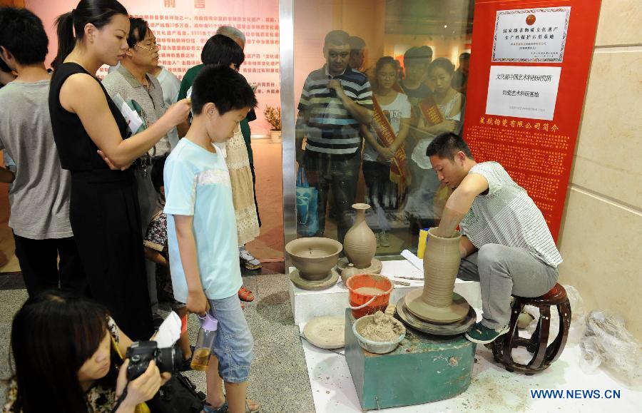 Visitors look at the process of making jun porcelain at an exhibition of intangible cultural heritages in the Henan Museum in Zhengzhou, capital of central China's Henan Province, June 8, 2013. The exhibition was held to mark the 8th National Cultural Heritage Day. (Xinhua/Li Bo)
