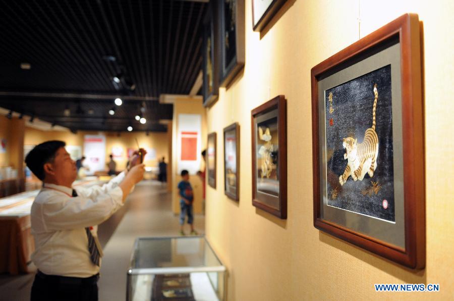 A visitor takes photo of paintings at an exhibition of intangible cultural heritages in the Henan Museum in Zhengzhou, capital of central China's Henan Province, June 8, 2013. The exhibition was held to mark the 8th National Cultural Heritage Day. (Xinhua/Li Bo)