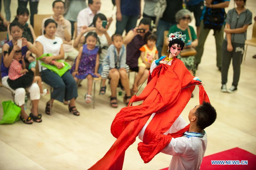 A performer operates a puppet during a Lingnan puppet show held by the Guangdong Provincial Puppet Art Theater at the Guangzhou Library to mark the 8th national Cultural Heritage Day in Guangzhou, capital of south China's Guangdong Province, June 8, 2013. (Xinhua/Mao Siqian)
