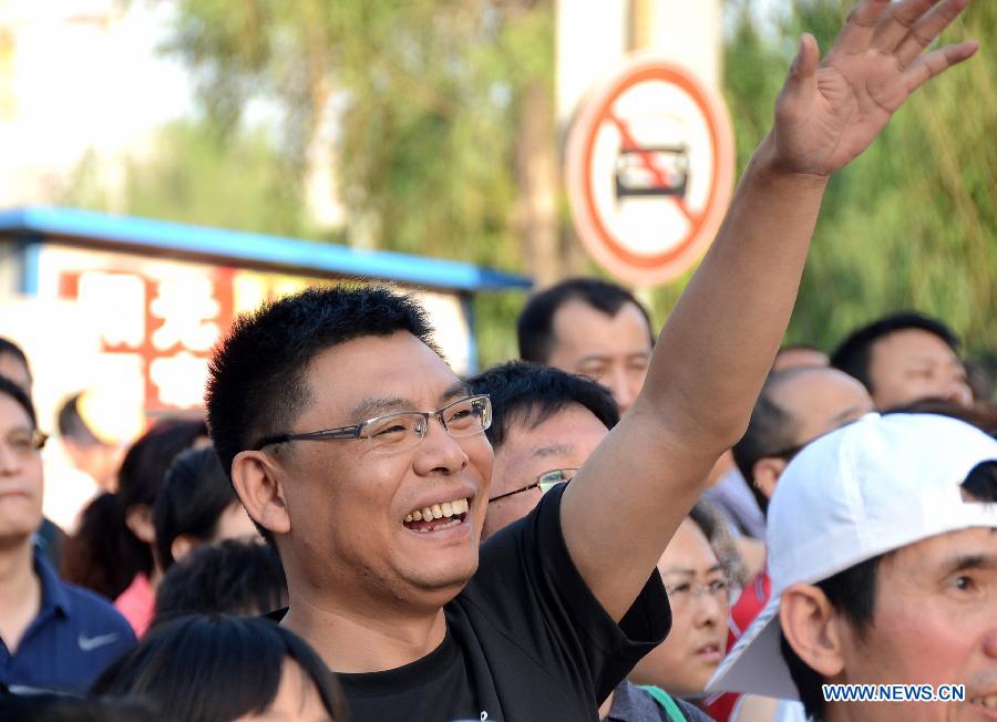 A parent waves to his child after the college entrance examination in the No. 17 Middle School in Changchun, capital of northeast China's Jilin Province, June 8, 2013. The 2013 national college entrance examination ended in some regions of China on Saturday. Approximately 9.12 million people took part in the exam this year. (Xinhua/Lin Hong) 