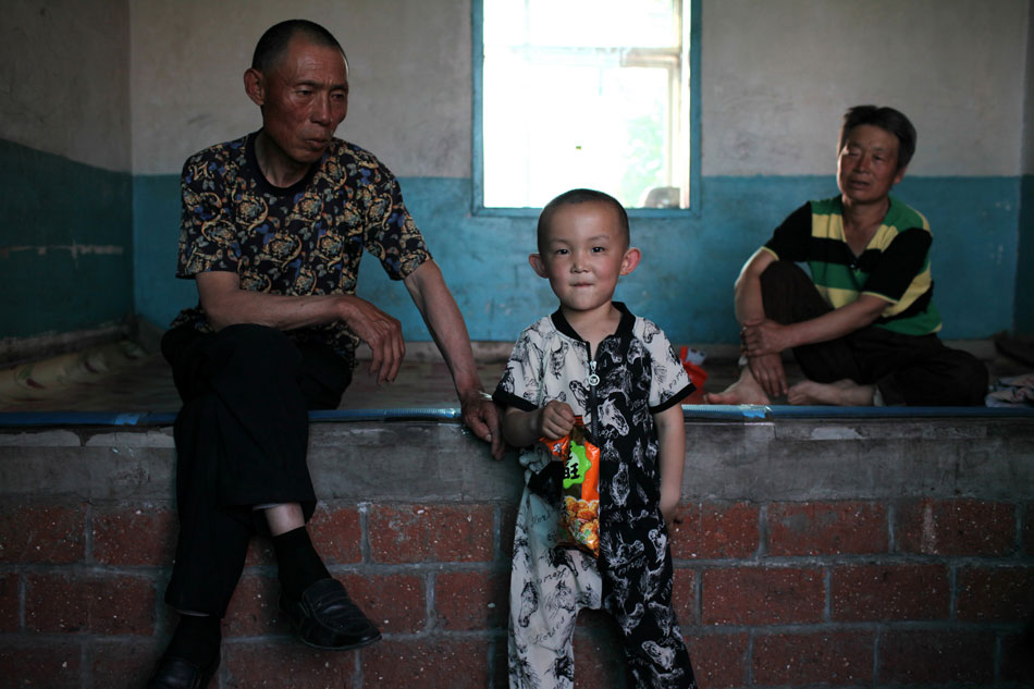 60-year-old Wu Yunfu (Right), 54-year-old Cui Guiwen(Left) and their 5-year-old grandson at home in Mishazi township of Dehui city, northeast China's Jilin province, June 3, 2013. Their son Wu Yanliang and daughter-in-law Tan Dan were both killed in the fire of Jilin Baoyuanfeng Poultry Company. The child was too young to understand what his parents' deaths mean to him. (Photo/Xinhua)