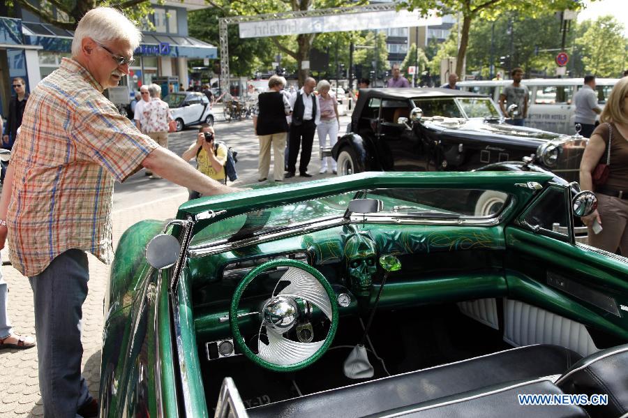 A visitor appreciates a classic old-timer car during a grand exhibition of the classic vintage cars, on the Kurfuerstendamm Avenue, in Berlin, Germany, June 8, 2013. Some 2,000 well-preserved and well-functioning classic vintage cars and limousines at least over 50-year-old are exhibited at the fair, with the motto "when luxury meets classics". (Xinhua/Pan Xu) 
