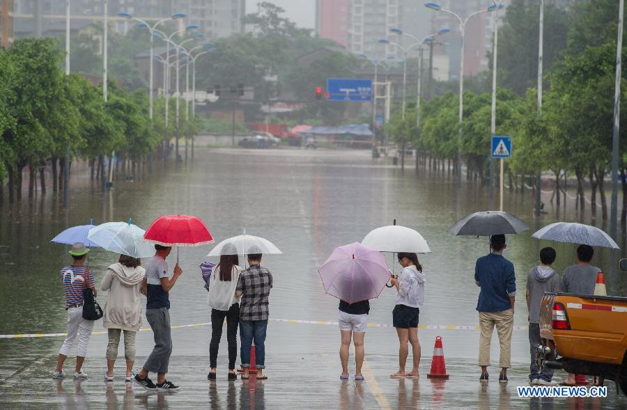 Pedestrians stop by a waterlogged road in southwest China's Chongqing Municipality, June 9, 2013. Heavy rainfall hit Chongqing as the city issued a red rainstorm warning here on Sunday. (Xinhua/Chen Cheng) 