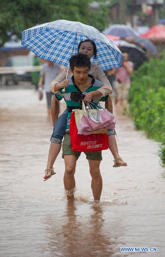 A man carries his girl friend on back as they pass a waterlogged road in southwest China's Chongqing Municipality, June 9, 2013. Heavy rainfall hit Chongqing as the city issued a red rainstorm warning here on Sunday.(Xinhua/Chen Cheng) 