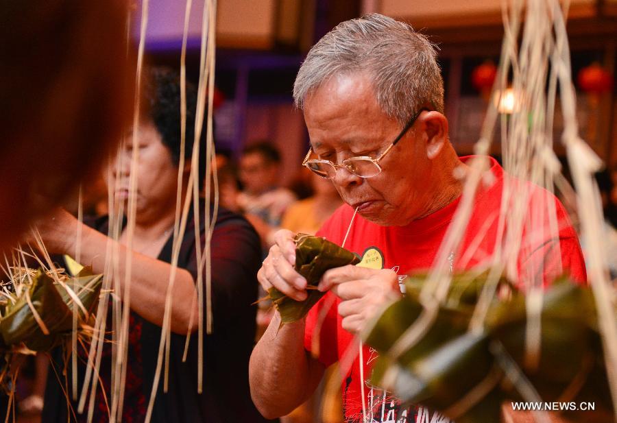 A contestant makes Zongzi, a pyramid-shaped dumpling made of glutinous rice wrapped in bamboo or reed leaves, during a contest in celebration of the upcoming Dragon Boat Festival in Kuala Lumpur, Malaysia, June 9, 2013. The contest was held by a local Chinese association to promote the traditional Chinese festival -- Dragon Boat Festival, which falls on the fifth day on the fifth month on the lunar calendar. (Xinhua/Chong Voon Chung) 