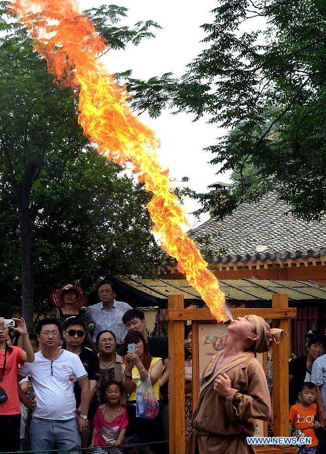 An actor sprays fire during an acrobatics performance on the Cultral Week for the annual Dragon Boat Festival in Kaifeng, central China's Henan Province, June 9, 2013. The week-long event, which was kicked off here Sunday, will held a series of activities of folk custom, showcasing local intangible cultural heritage to tourists. (Xinhua/Wang Song)