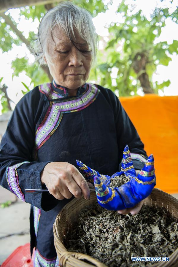 An old woman makes a traditional sachet to celebrate the upcoming Dragon Boat Festival in a folk workshop in Baise City, south China's Guangxi Zhuang Autonomous Region, June 9, 2013. (Xinhua/Wei Wanzhong) 