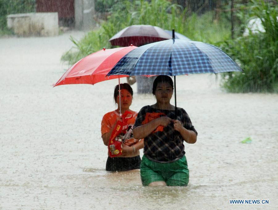 People walk on a flooded road in Rongan County, Liuzhou, south China's Guangxi Zhuang Autonomous Region, June 9, 2013. A new round of torrential rainfall hit Guangxi on Sunday, and local meteorological authorities issued a blue alert for rainstorms. China has a four-color warning system for strong rain, with red being the most serious, followed by orange, yellow and blue. (Xinhua/Huang Guoliang) 
