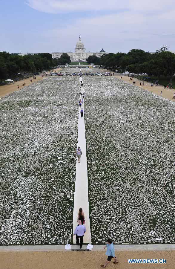 Visitors walk among bones during a demonstration named "One Million Bones" on the National Mall in Washington D.C., capital of the United States, June 9, 2013. One million handmade human bones, created by students, artists, and activists were laid during the weekend on the National Mall as a symbolic mass grave and a visible petition to end genocide and mass atrocities. (Xinhua/Zhang Jun)