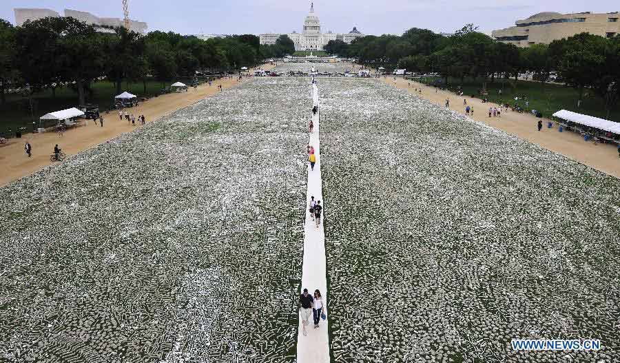 Visitors walk among bones during a demonstration named "One Million Bones" on the National Mall in Washington D.C., capital of the United States, June 9, 2013. One million handmade human bones, created by students, artists, and activists were laid during the weekend on the National Mall as a symbolic mass grave and a visible petition to end genocide and mass atrocities. (Xinhua/Zhang Jun)