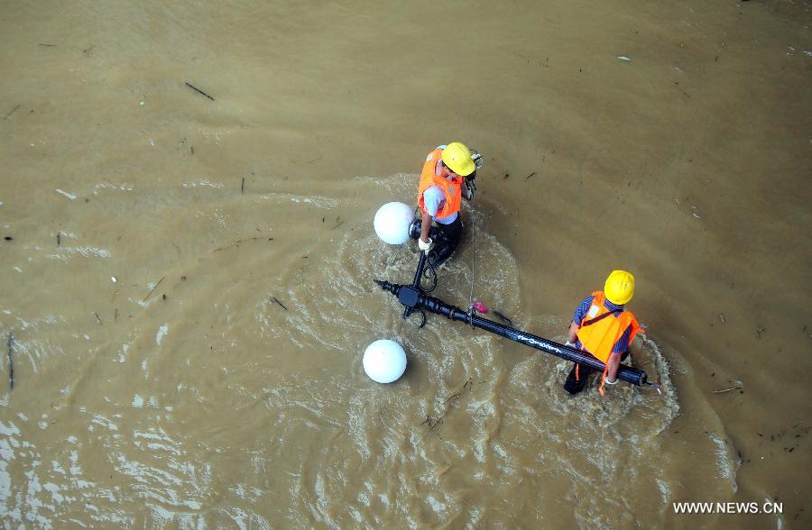Workers remove a damaged streetlight on a flooded road in Liuzhou City, south China's Guangxi Zhuang Autonomous Region, June 10, 2013. Lingering heavy rainfalls in recent days has caused the Liujiang River's water level to rise to 82.7 meters in urban Liuzhou by 11 a.m. Beijing Time (0300 GMT) on Monday, 0.2 meters higher than the warning level. (Xinhua/Huang Xiaobang) 