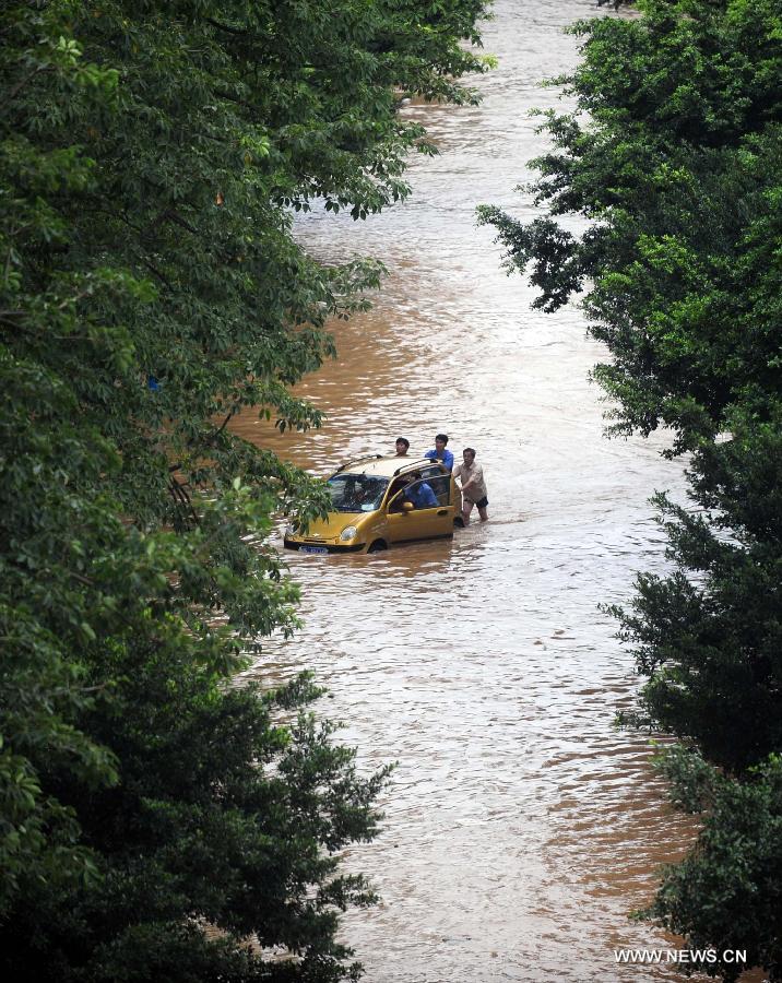 Citizens push a car on a flooded road in Liuzhou City, south China's Guangxi Zhuang Autonomous Region, June 10, 2013. Lingering heavy rainfalls in recent days has caused the Liujiang River's water level to rise to 82.7 meters in urban Liuzhou by 11 a.m. Beijing Time (0300 GMT) on Monday, 0.2 meters higher than the warning level. (Xinhua/Huang Xiaobang) 