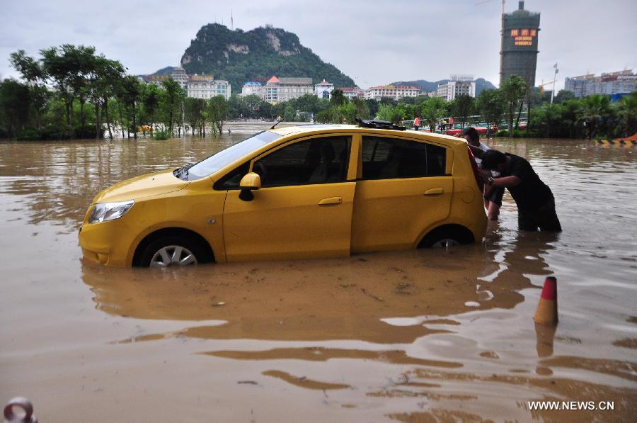 Citizens push a car on a flooded road in Liuzhou City, south China's Guangxi Zhuang Autonomous Region, June 10, 2013. Lingering heavy rainfalls in recent days has caused the Liujiang River's water level to rise to 82.7 meters in urban Liuzhou by 11 a.m. Beijing Time (0300 GMT) on Monday, 0.2 meters higher than the warning level. (Xinhua/Li Shuhou) 
