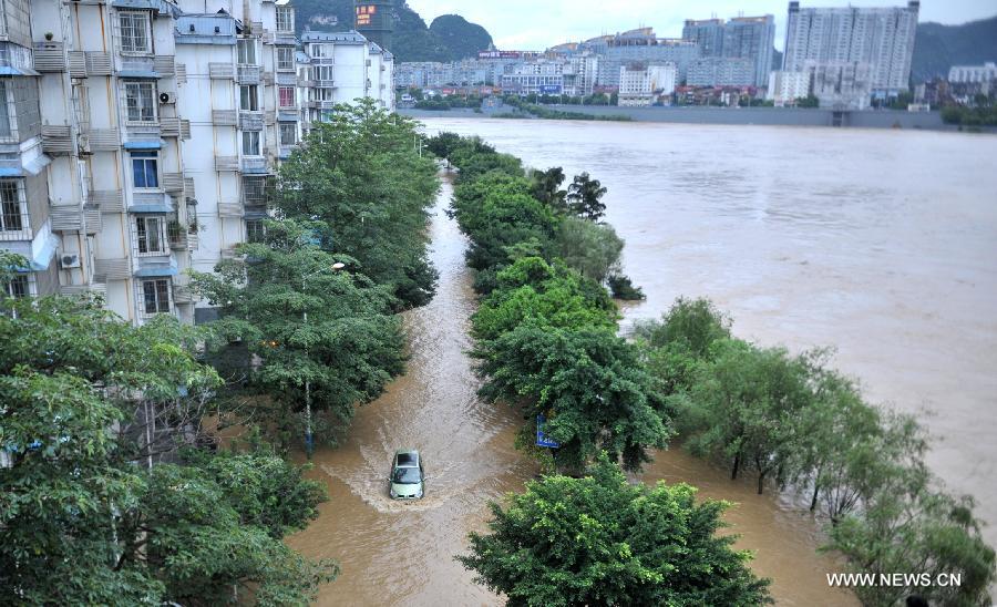 A vehicle moves on a flooded road in Liuzhou City, south China's Guangxi Zhuang Autonomous Region, June 10, 2013. Lingering heavy rainfalls in recent days has caused the Liujiang River's water level to rise to 82.7 meters in urban Liuzhou by 11 a.m. Beijing Time (0300 GMT) on Monday, 0.2 meters higher than the warning level. (Xinhua/Li Hanchi)